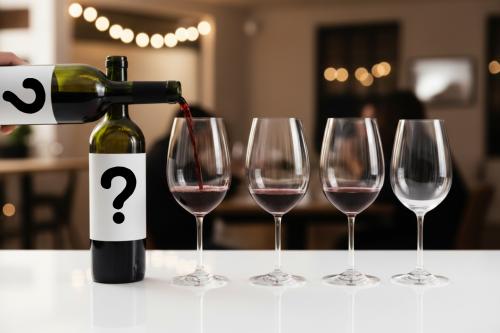 4 glasses of wine with two white labels with question marks for a blind tasting