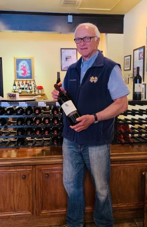 Louis Lucas with a bottle of Notre Dame wine at the wine tasting room in Solvang CA 